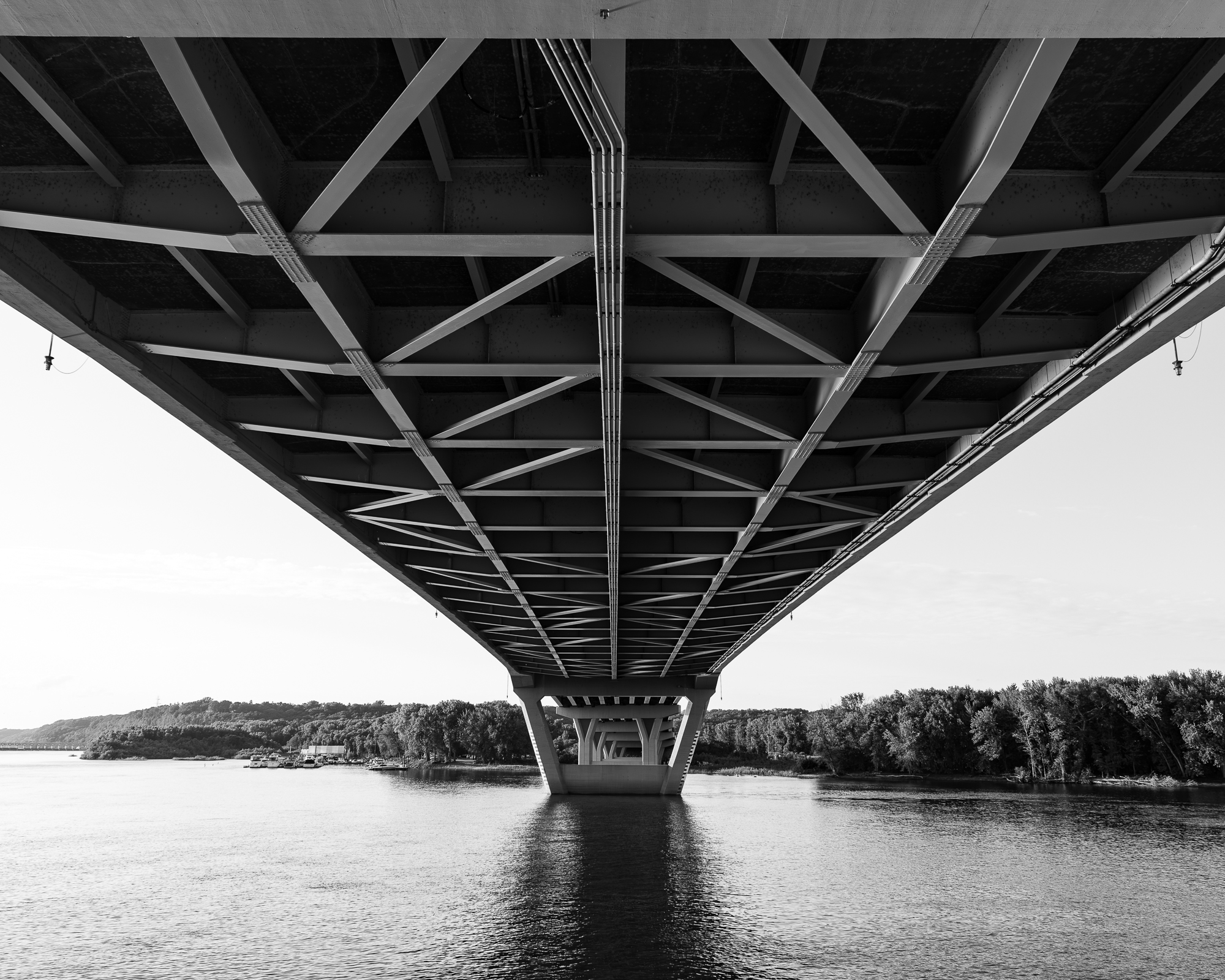 Girders form a pattern underneath a bridge in black and white.